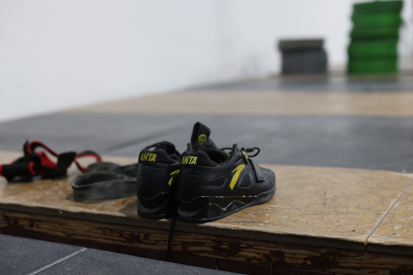 Zapatillas de halterofilia Anta y straps sobre tarima de madera en sala de drop-in para levantamientos olímpicos en Barcelona.