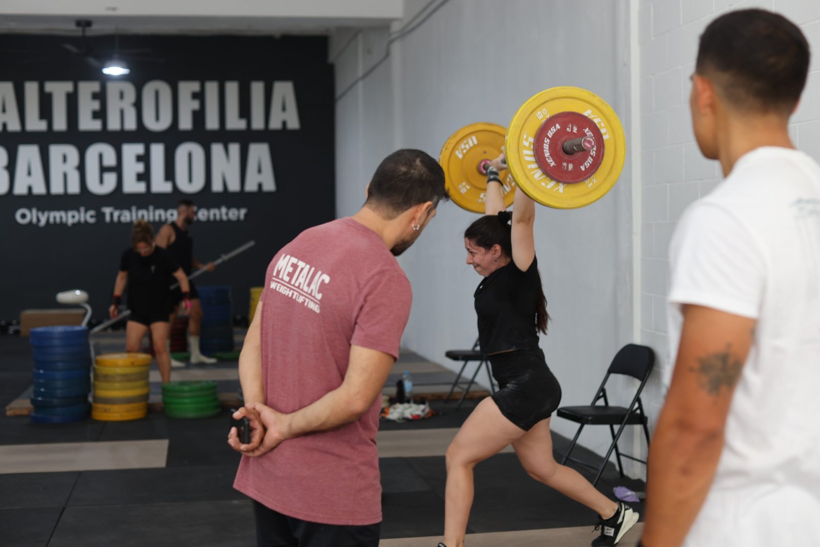 El coach Ronald Paz corrigiendo la posición de tijera en un Clean and Jerk a una atleta en el centro de halterofilia de Barcelona.
